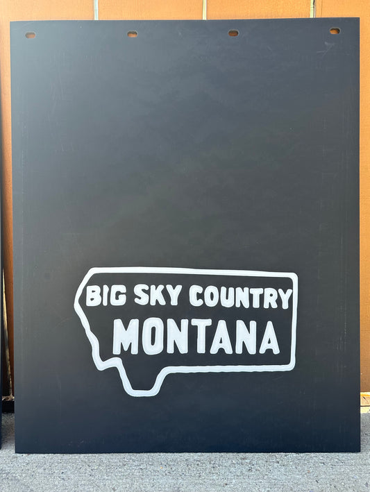 Black mudflaps with 'Big Sky Country Montana' text on a wooden background