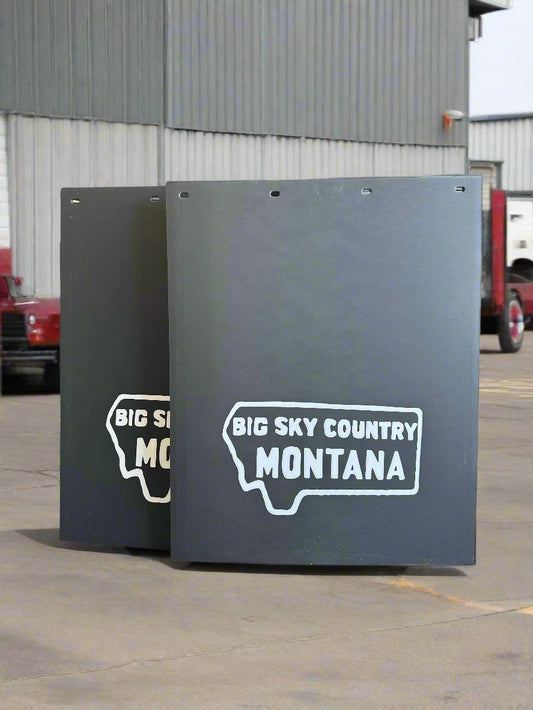 Black mudflaps with 'Big Sky Country Montana' text and logo on a concrete floor.