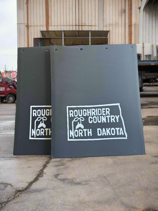 mudflaps with 'Roughrider Country North Dakota' logo on a concrete surface.