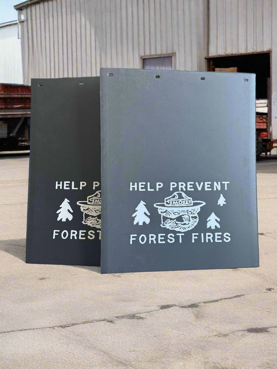 Mudflaps with white text and graphics on a concrete floor.