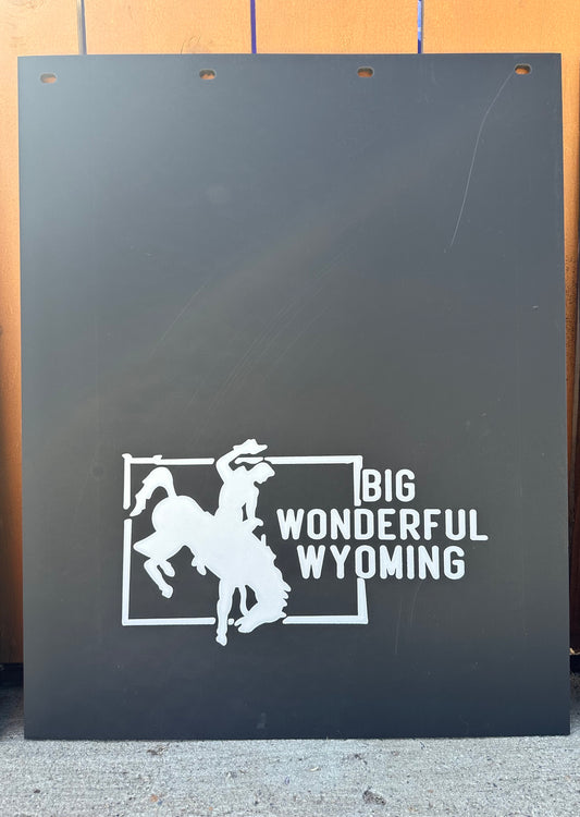 Black mudflaps with white graphic and text 'Big Wonderful Wyoming' on a wooden background